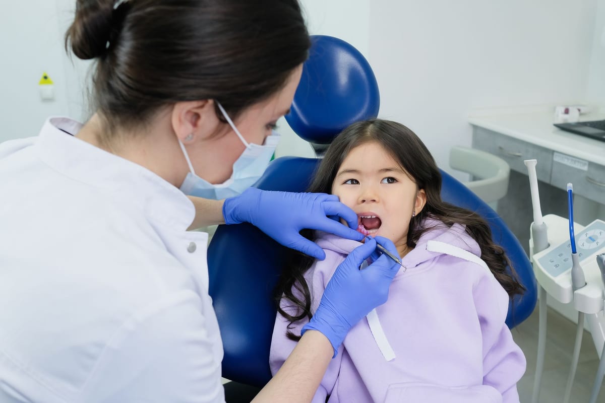 A young child having her teeth checked in a dental chair